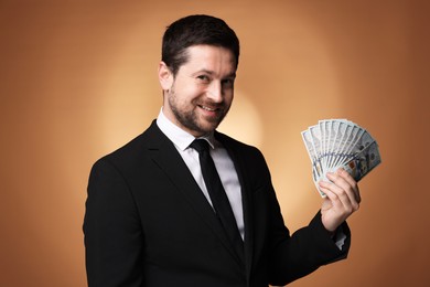 Photo of Happy greedy banker with dollar banknotes on golden background