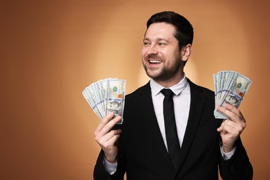 Photo of Happy greedy banker with dollar banknotes on golden background. Space for text