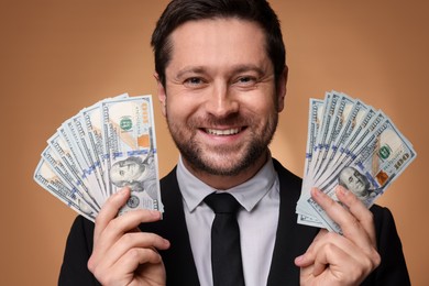 Photo of Happy greedy banker with dollar banknotes on golden background, closeup