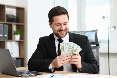 Photo of Greedy banker counting money and smiling at table in office