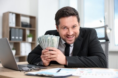 Photo of Happy greedy banker with dollar banknotes at table in office
