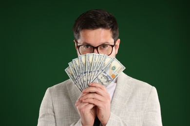 Photo of Greedy banker with dollar banknotes on green background