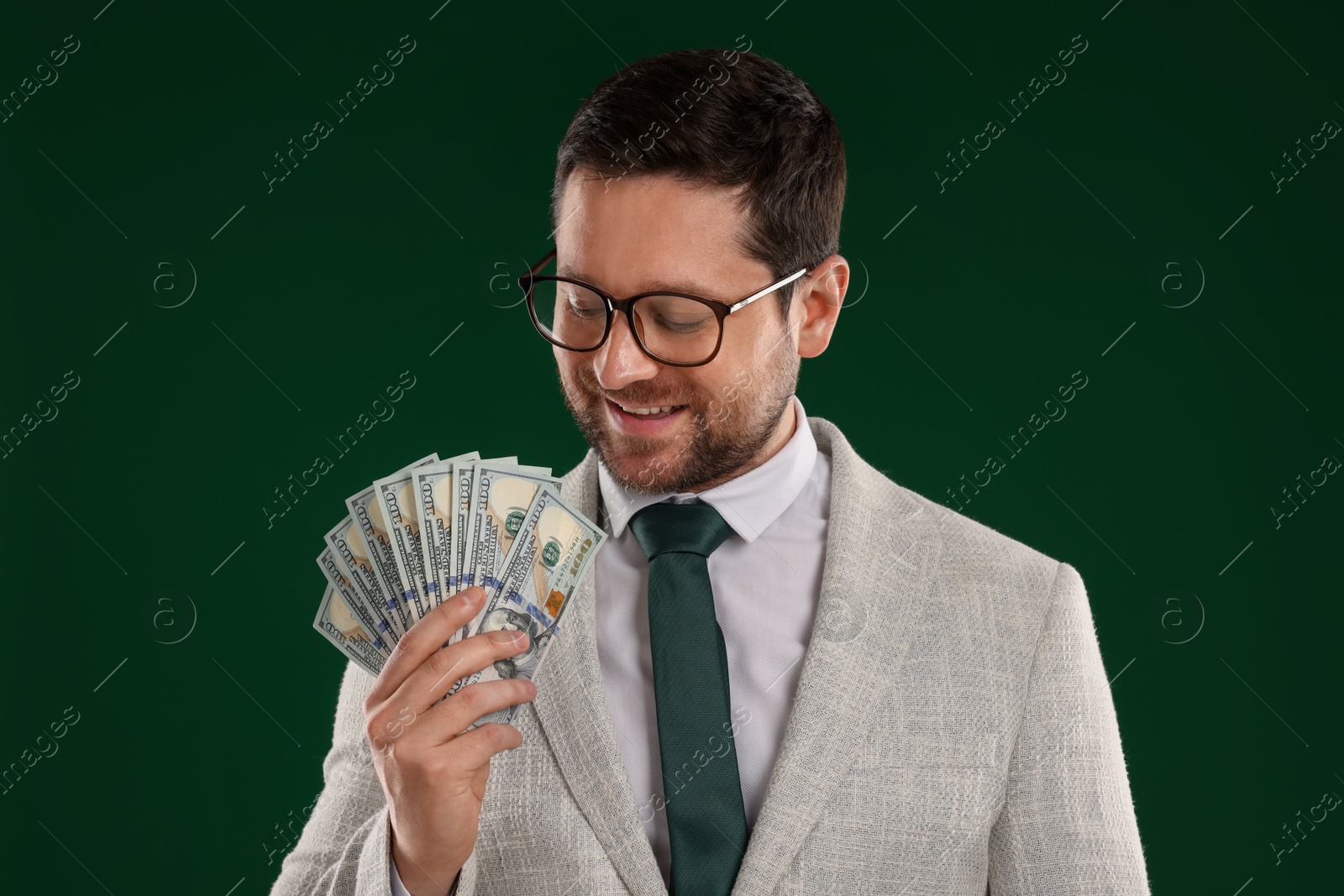 Happy greedy banker with dollar banknotes on green background Photo of Happy greedy banker with dollar banknotes on green background
