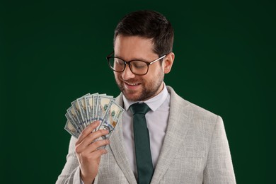 Photo of Happy greedy banker with dollar banknotes on green background