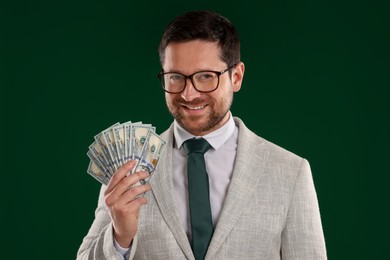 Photo of Happy greedy banker with dollar banknotes on green background