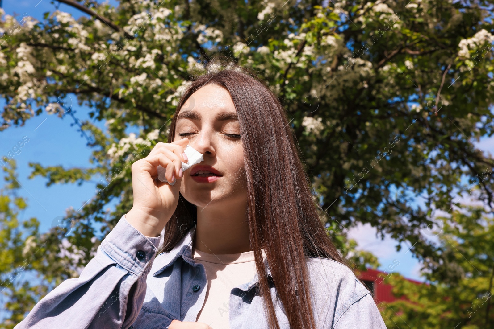 Woman with paper tissue suffering from seasonal pollen allergy near blossoming tree on spring day, low angle view Photo of Woman with paper tissue suffering from seasonal pollen allergy near blossoming tree on spring day, low angle view
