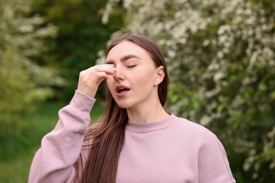 Photo of Woman suffering from seasonal pollen allergy near blossoming shrub on spring day