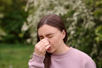 Photo of Woman suffering from seasonal pollen allergy near blossoming shrub on spring day, space for text