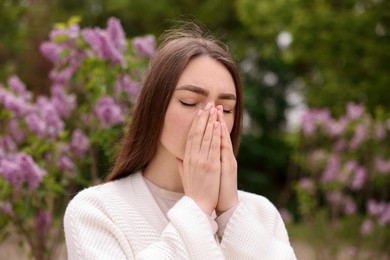 Photo of Woman suffering from seasonal pollen allergy near blossoming shrub on spring day