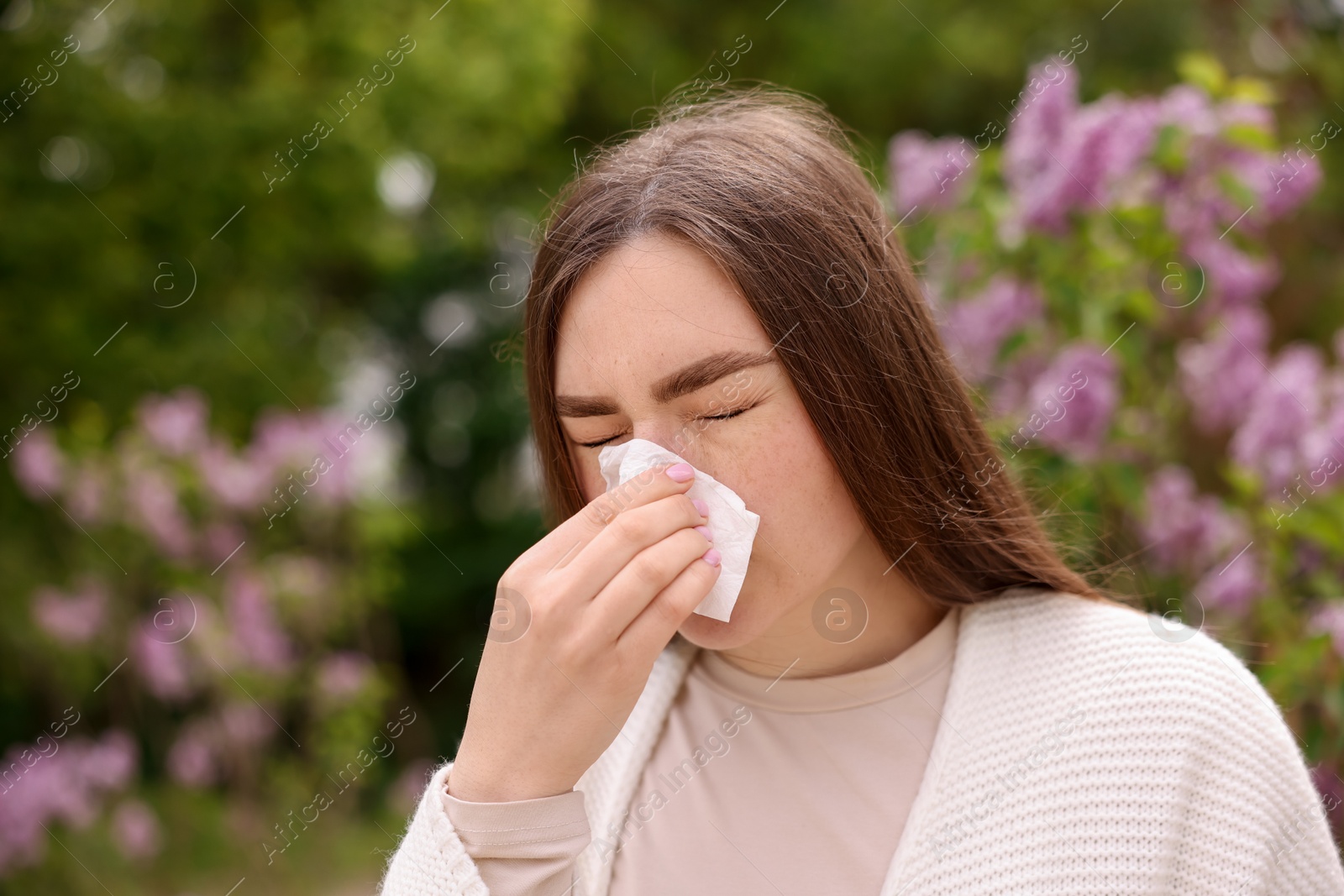 Woman with paper tissue suffering from seasonal pollen allergy near blossoming shrub on spring day, space for text Photo of Woman with paper tissue suffering from seasonal pollen allergy near blossoming shrub on spring day, space for text