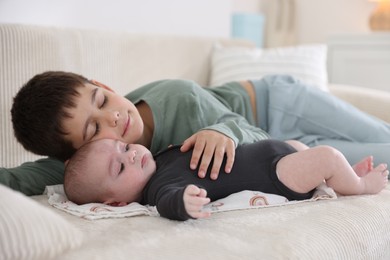 Photo of Cute little brothers on sofa at home