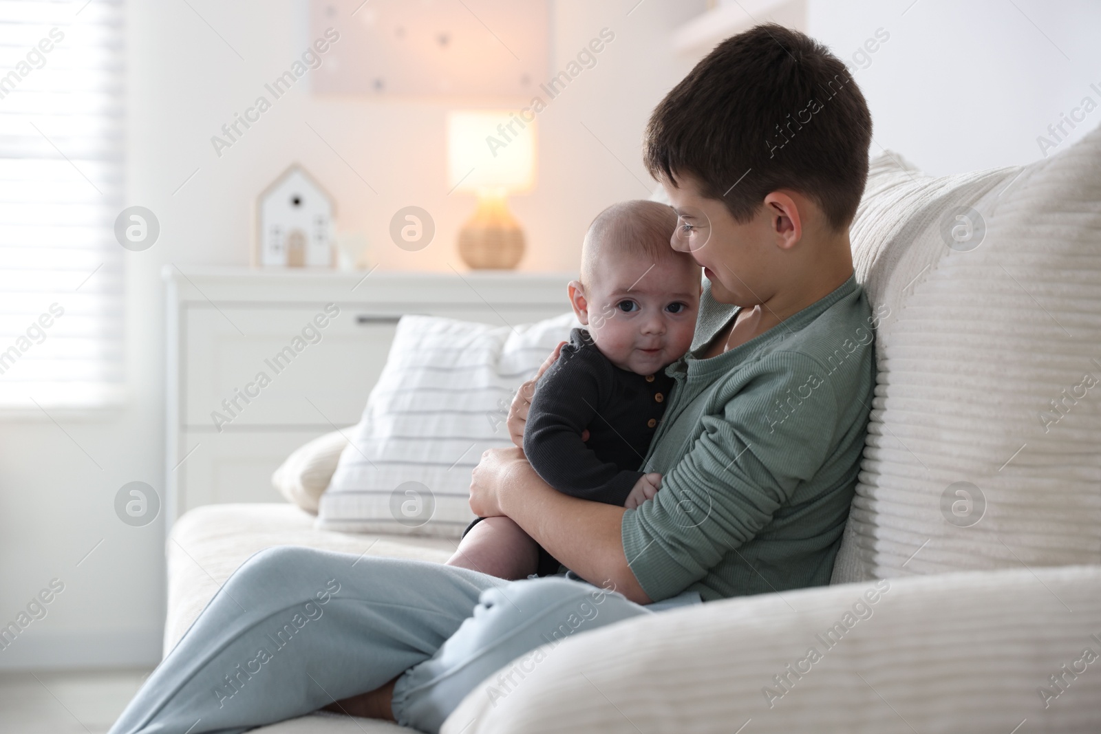 Cute little brothers sitting on sofa at home Photo of Cute little brothers sitting on sofa at home