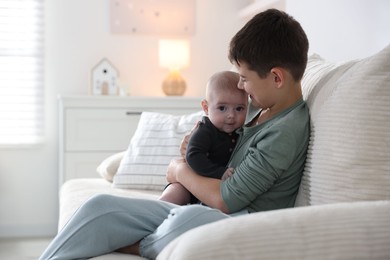 Photo of Cute little brothers sitting on sofa at home