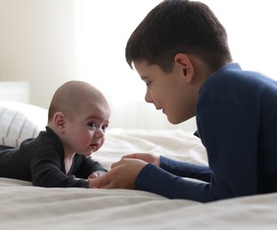 Photo of Cute little brothers holding hands on bed at home