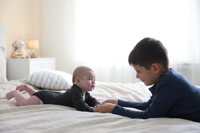Photo of Cute little brothers holding hands on bed at home