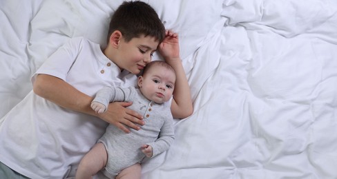 Photo of Cute little brothers on bed, top view. Space for text