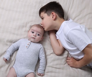 Photo of Cute little brothers on bed, top view