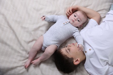 Photo of Cute little brothers on bed, top view