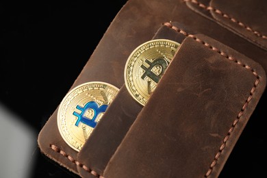 Photo of Cryptocurrency. Bitcoins in wallet on black mirror surface, above view