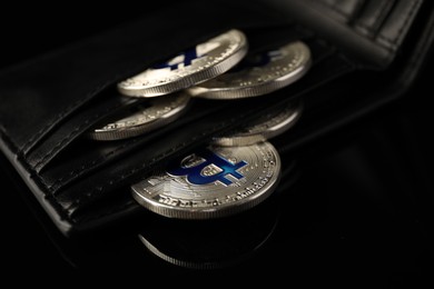 Photo of Cryptocurrency. Bitcoins in wallet on black mirror surface, closeup