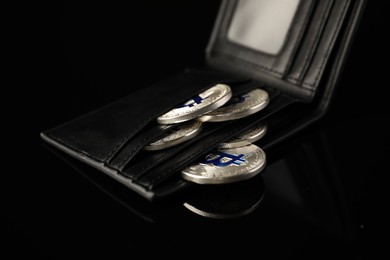 Photo of Cryptocurrency. Bitcoins in wallet on black mirror surface, closeup