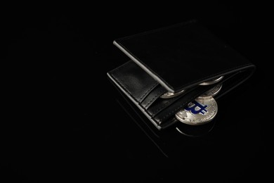 Photo of Cryptocurrency. Bitcoins in wallet on black mirror surface, closeup. Space for text