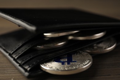 Photo of Cryptocurrency. Bitcoins in wallet on wooden background, closeup