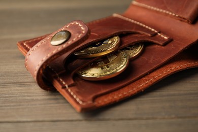 Photo of Cryptocurrency. Bitcoins in wallet on wooden background, closeup