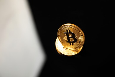 Photo of Cryptocurrency. Bitcoins on black mirror surface, above view. Space for text