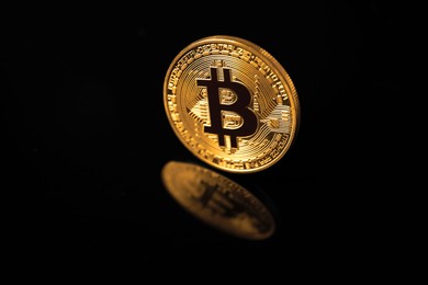 Photo of Cryptocurrency. Bitcoin on black mirror surface, closeup