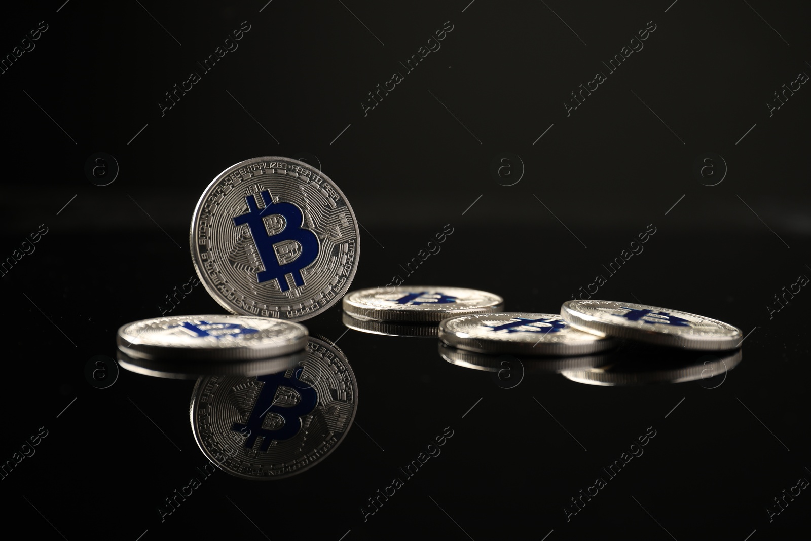 Cryptocurrency. Bitcoins on black mirror surface, closeup Photo of Cryptocurrency. Bitcoins on black mirror surface, closeup