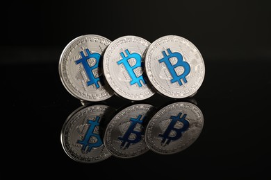 Photo of Cryptocurrency. Bitcoins on black mirror surface, closeup