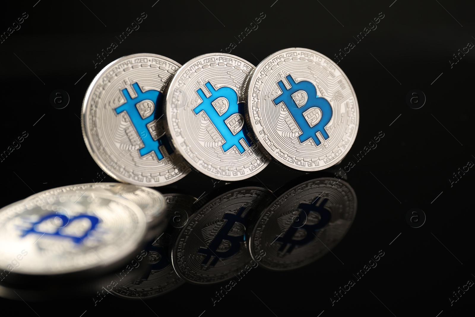Cryptocurrency. Bitcoins on black mirror surface, closeup Photo of Cryptocurrency. Bitcoins on black mirror surface, closeup