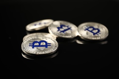 Photo of Cryptocurrency. Bitcoins on black mirror surface, closeup