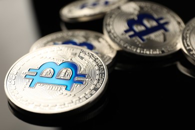 Photo of Cryptocurrency. Bitcoins on black mirror surface, closeup