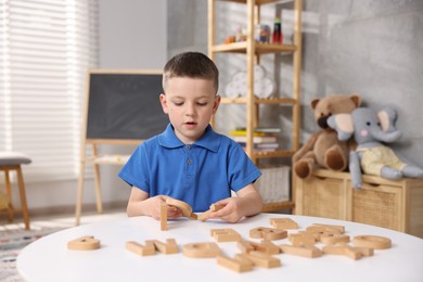 Photo of Dyslexia. Little boy learning letters at table indoors