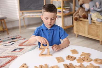 Photo of Dyslexia. Little boy learning letters at table indoors