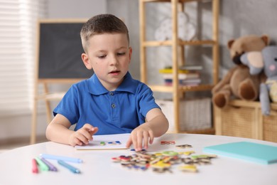 Photo of Dyslexia. Little boy learning letters at table indoors
