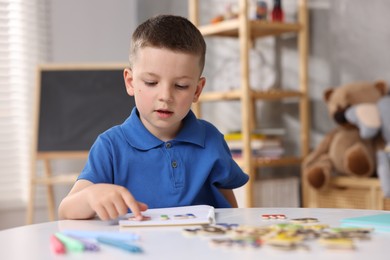 Photo of Dyslexia. Little boy learning letters at table indoors