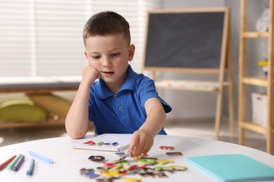 Photo of Dyslexia. Little boy learning letters at table indoors