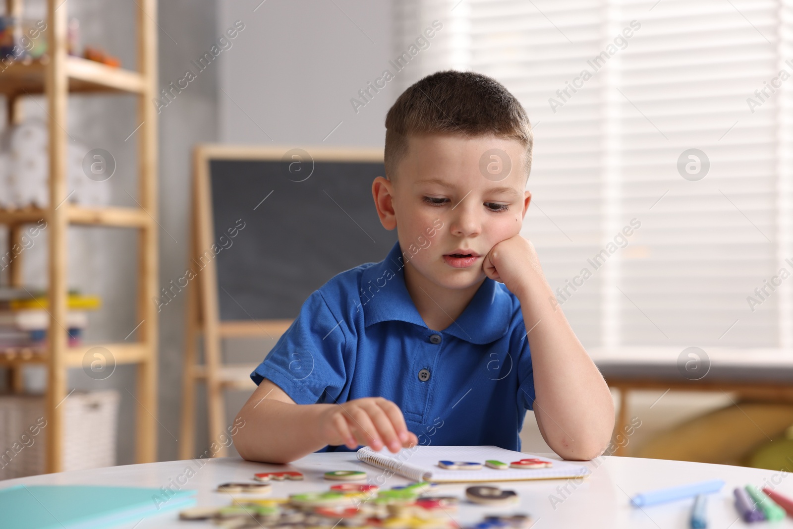 Dyslexia. Little boy learning letters at table indoors Photo of Dyslexia. Little boy learning letters at table indoors