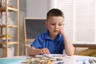 Photo of Dyslexia. Little boy learning letters at table indoors