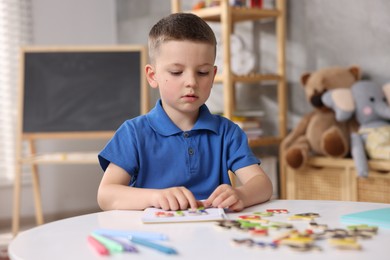 Photo of Dyslexia. Little boy learning letters at table indoors