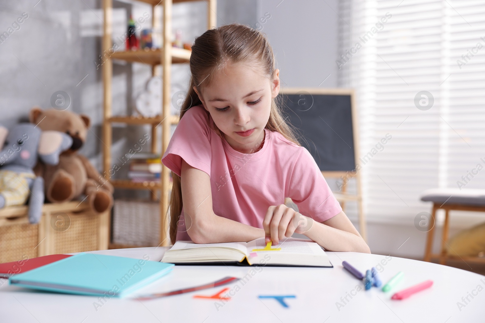Dyslexia. Little girl reading book at table indoors Photo of Dyslexia. Little girl reading book at table indoors