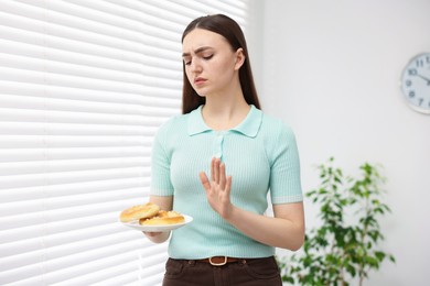 Photo of Gluten free diet. Young woman refusing pretzels indoors