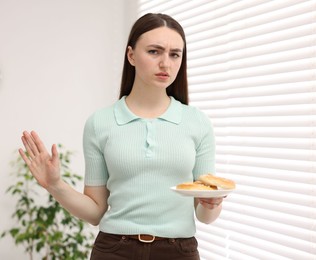 Photo of Gluten free diet. Young woman refusing pretzels indoors