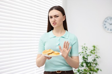 Photo of Gluten free diet. Young woman refusing pretzels indoors