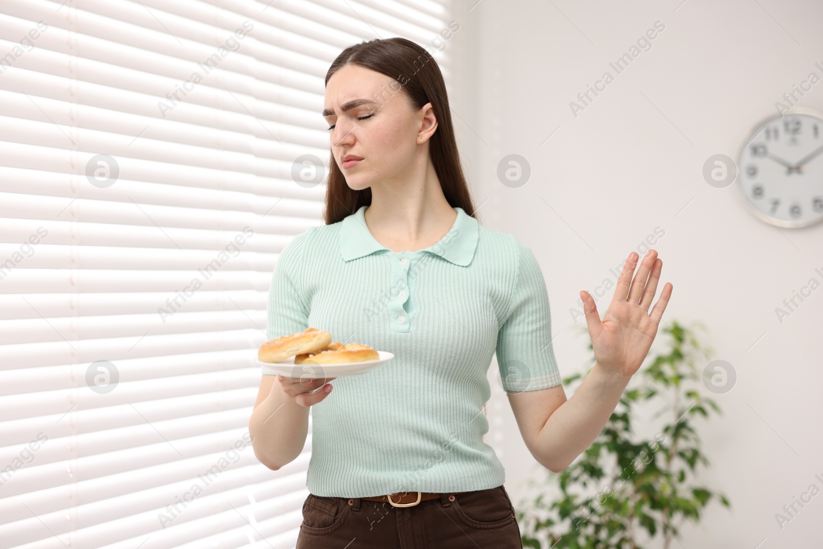 Gluten free diet. Young woman refusing pretzels indoors Photo of Gluten free diet. Young woman refusing pretzels indoors