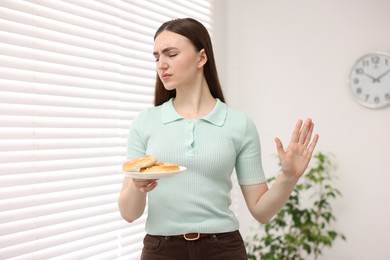 Photo of Gluten free diet. Young woman refusing pretzels indoors