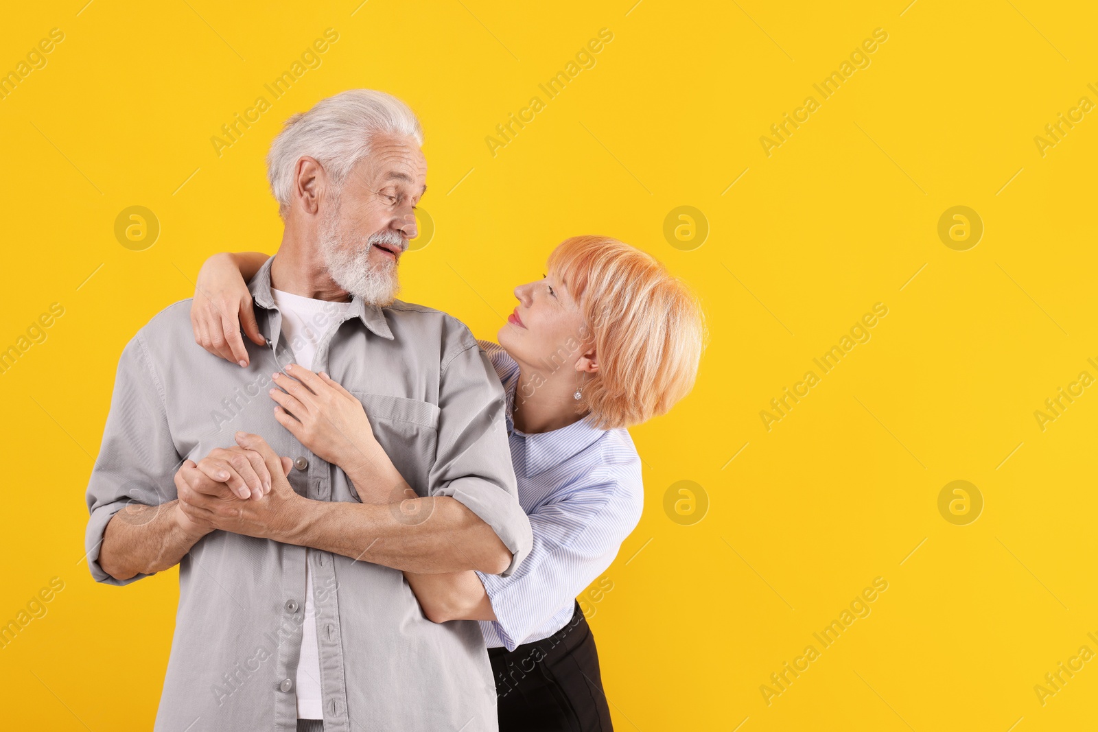 Lovely senior couple together on yellow background, space for text Photo of Lovely senior couple together on yellow background, space for text
